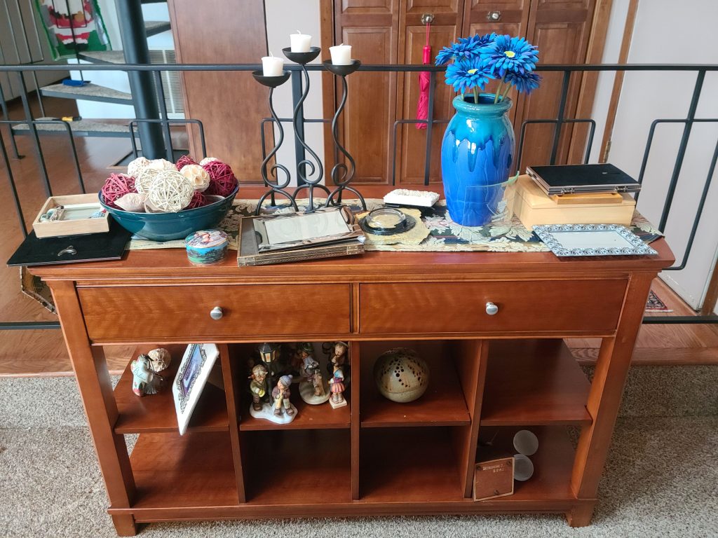 Console table with candlesticks, a blue vase and collectibles for a silent auction