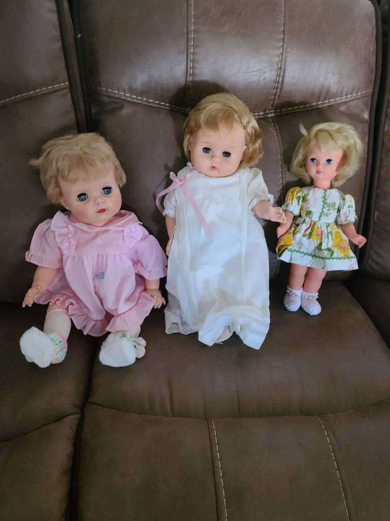 Three vintage dolls in dresses at an estate sale