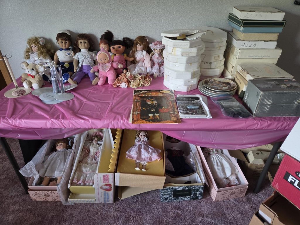 Doll collection displayed on pink tables at an estate sale